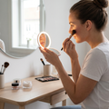 Person applying makeup using an LED vanity mirror