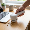 Person using a mini desk vacuum on a keyboard