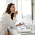 Person applying hydrogel under eye patches at a bathroom vanity
