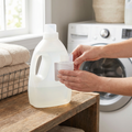 Person clipping a detergent cup holder onto a laundry detergent bottle