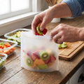 Person filling a reusable silicone food storage bag with fruit