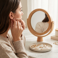 Person putting on a hoop earring in front of a mirror